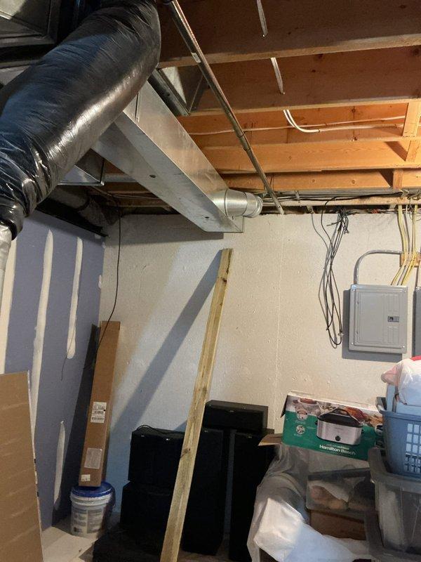 Responded to service call for reported water leak in basement originating from equipment above furnace. Upon arrival, inspected the area and documented conditions with photos showing HVAC ductwork, copper piping, and mechanical systems in basement utility space. Unit had been shut off prior to arrival to prevent further damage. Assessed the source of the leak and surrounding components to determine necessary repairs.