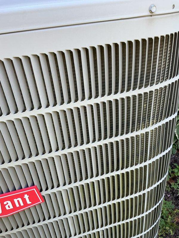 Completed routine HVAC maintenance on Bryant outdoor condensing unit. Inspected condenser coils, verified proper airflow through louvered panels, and documented unit condition with photographs showing equipment in good operational status with minimal debris accumulation.