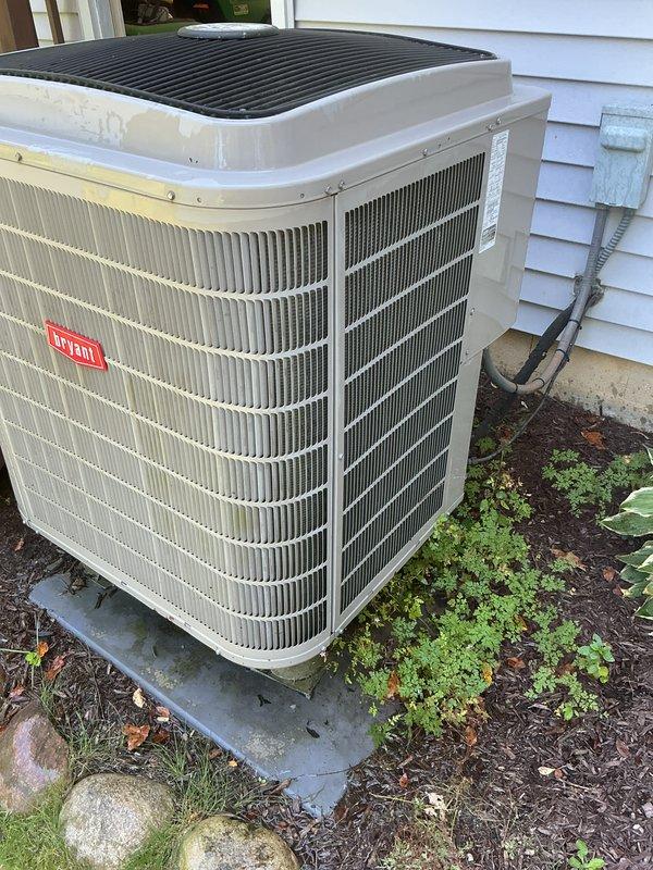 Completed routine HVAC maintenance on Bryant outdoor condensing unit. Inspected condenser coils, verified proper airflow through louvered panels, and documented unit condition with photographs showing equipment in good operational status with minimal debris accumulation.