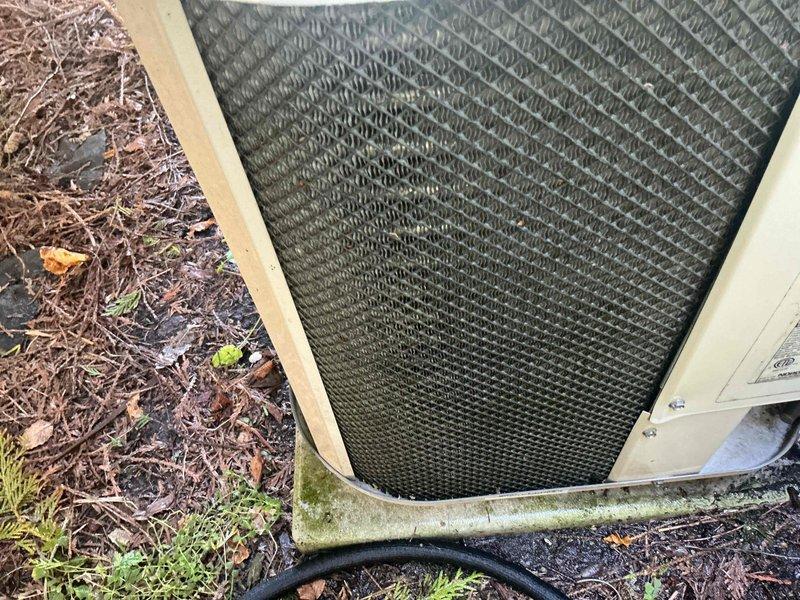 Completed annual AC tune-up and inspection on Gibson outdoor condensing unit. Performed comprehensive system evaluation including visual inspection of condenser coil through protective grille, verified refrigerant line connections and insulation integrity, and assessed unit mounting and pad condition. Unit displayed normal operational wear with minor debris accumulation on grille mesh and weathered copper refrigerant lines showing typical outdoor patina. No mechanical issues, refrigerant leaks, or performance concerns identified during inspection. System operating within normal parameters with all components functioning properly.