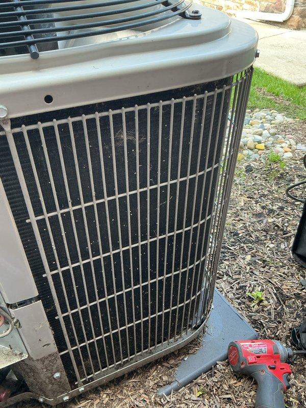 Completed follow-up tune-up service on residential HVAC system. Cleaned outdoor condenser coils using extended 100-foot hose to remove accumulated dirt and debris from vertical grille fins. Inspected indoor furnace components with access panel removed, verifying proper operation of blower motor, electrical connections, gas line, and PVC condensate drainage system—all components found in normal working condition.