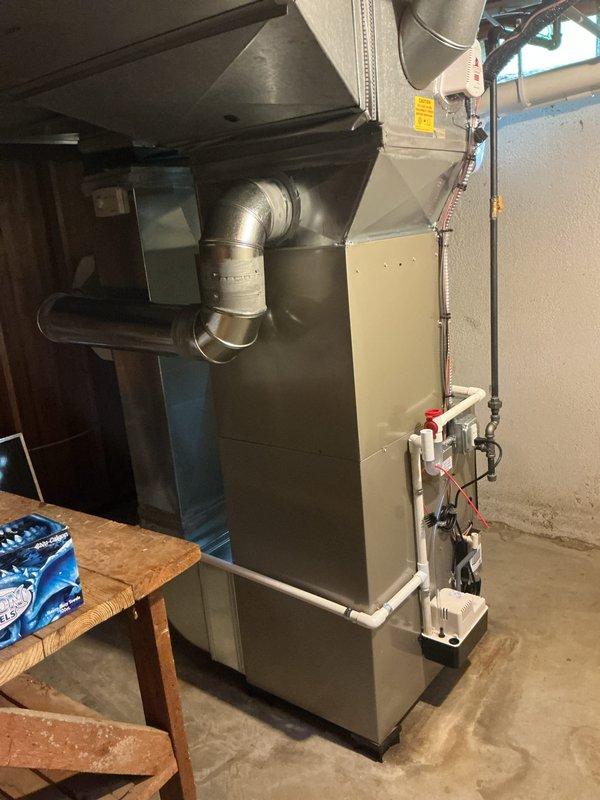 # HVAC Complete System Installation

Successfully completed a full HVAC system installation in a residential basement utility room. Installed a new high-efficiency furnace unit with properly configured white PVC venting system routed through the structure for intake and exhaust. Connected silver metallic supply ductwork with appropriate transitions and elbows to ensure proper airflow distribution throughout the home. Integrated a whole-home humidifier into the system with dedicated water supply lines and drainage connections to maintain optimal indoor humidity levels during heating season. Installed an air purification system to enhance indoor air quality and filtration. All ductwork connections were sealed and secured, including black flexible return air ducting. Electrical connections were completed to code with proper wire management and safety disconnects. Verified all PVC condensate drainage lines were properly pitched and secured. System startup and commissioning performed with a