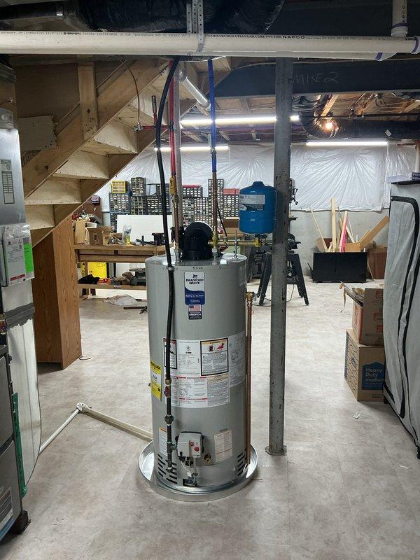 # Gas Water Heater Installation

Successfully installed a new gas-fired tanked water heater in the basement utility area. The installation included proper positioning of the unit on the concrete floor, connection of hot and cold water supply lines using PEX tubing (red for hot, blue for cold), and secure mounting of all plumbing connections to the ceiling joists with appropriate clips and fasteners. Gas line connection was completed in accordance with local code requirements, and all necessary safety labels and manufacturer specifications were verified on the unit. The water supply lines were routed through the existing ceiling infrastructure alongside the vertical PVC drainage system. All connections were tested for leaks and proper operation, and the unit was fired up and confirmed to be heating water correctly before completion.