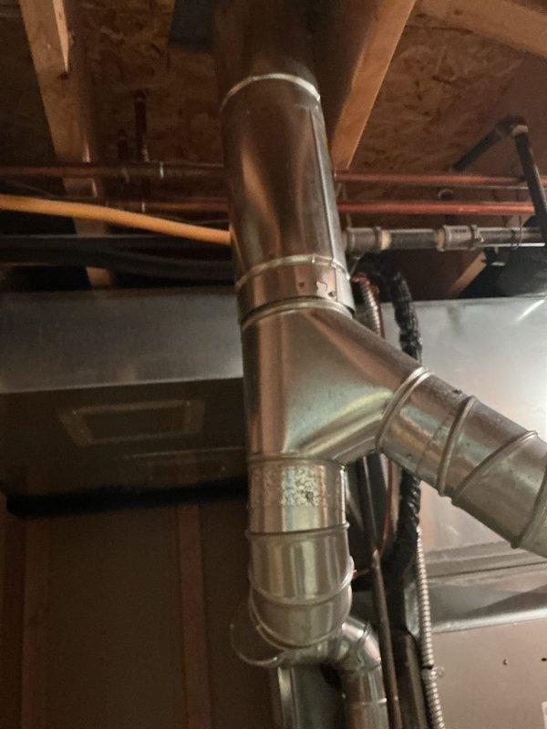Completed installation of new air conditioning system with evaporator coil in basement utility area. Installed condensate drain line with proper floor drain connection, routed refrigerant lines and electrical connections, and configured metal venting system with secure mounting brackets and band clamps to ensure proper exhaust flow. System tested and verified operational upon completion.