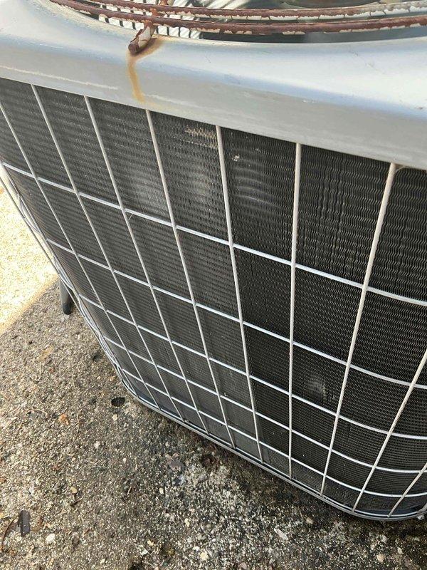 Completed scheduled air conditioning maintenance on outdoor condenser unit. Inspected condenser coils, fins, and protective guard assembly; noted rust and corrosion present on top metal guard but unit operational. System tested and confirmed functioning properly in cooling mode.