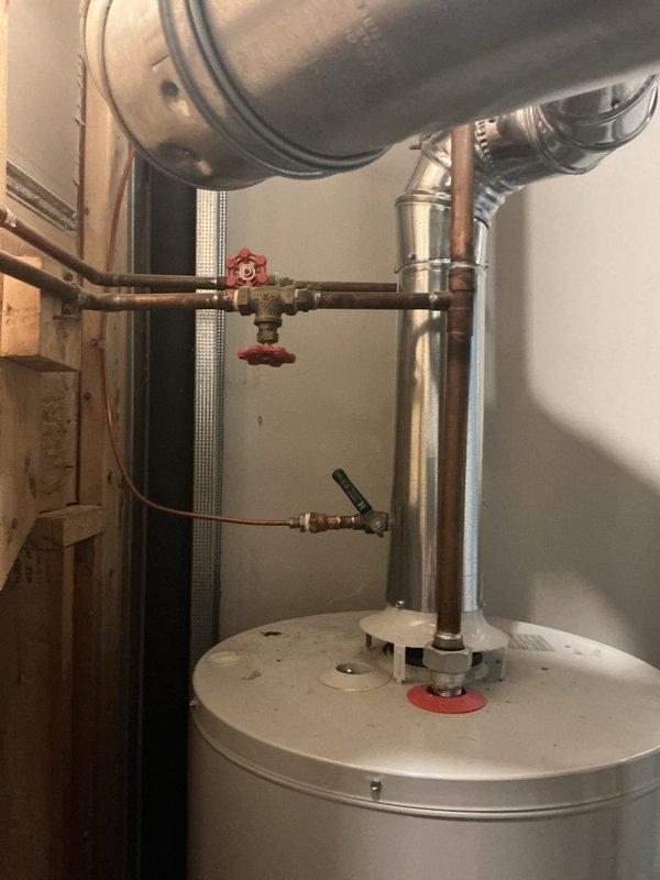 Responded to service call for reported boiler leak. Upon inspection, determined unit was actually an A.O. Smith residential water heater, not a boiler system. Conducted thorough visual assessment of the water heater installation, examining all piping connections, valves, and tank integrity. Inspected copper supply lines, inlet/outlet connections at top of tank, red-handled isolation valve, and secondary valve assembly. Checked base of unit and surrounding floor area for signs of active leaking or water damage. Documented equipment condition and plumbing configuration with photographs for service records and potential repair recommendations.