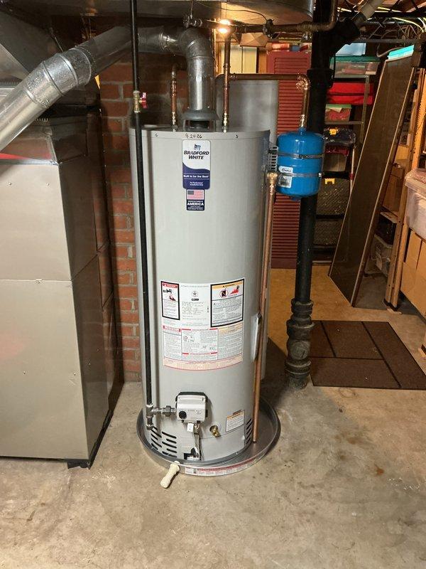 Completed installation of Bradford White gas-fired water heater in residential basement utility area. Unit was properly positioned on concrete floor, connected to existing gas and water supply lines with code-compliant piping, and vented through flexible duct system. All manufacturer safety labels and specifications verified, drain valve installed at base, and unit tested for proper operation.