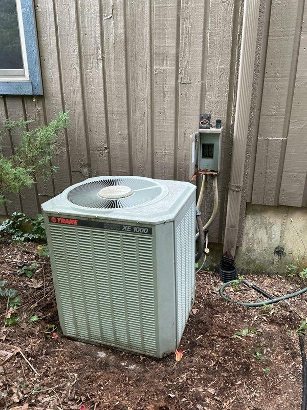Responded to service call for air conditioning unit not cooling properly. Upon arrival, found 15-year-old Trane XE 1000 system with evaporator coil freezing issue. Coil was thawed at time of inspection. Performed diagnostic evaluation to identify root cause of freezing condition. Assessed airflow, refrigerant levels, and system operation. Documented unit condition with photos showing outdoor condenser placement and electrical disconnect. Collected service fee and provided customer with repair recommendations. Follow-up appointment scheduled to address necessary repairs and prevent future coil freezing.