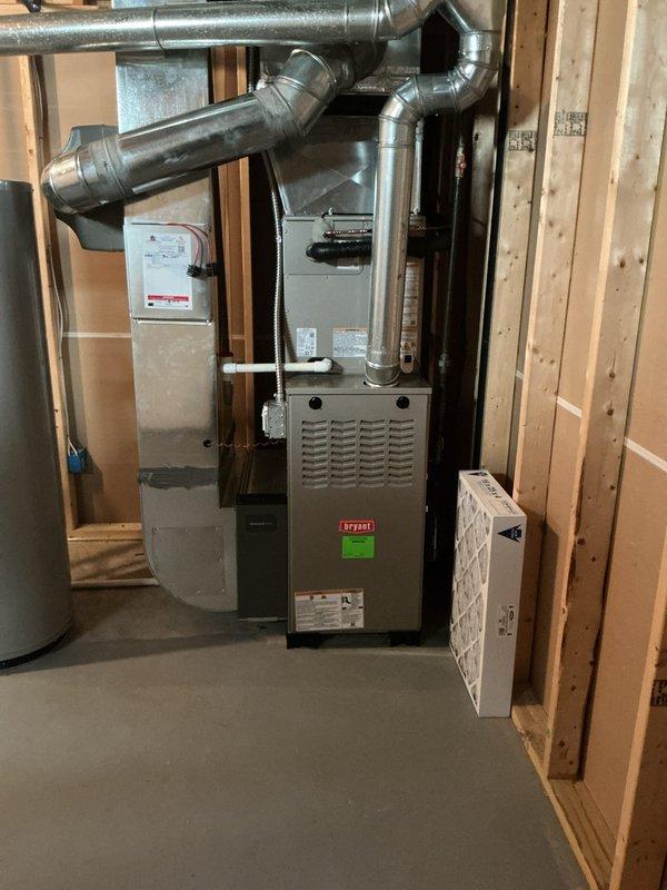 Completed installation of new air conditioning system with evaporator coil in residential basement utility area. System was properly integrated with existing Bryant furnace, including connection of refrigerant lines, condensate drainage, and electrical components. All ductwork connections were secured to the new evaporator coil mounted above the furnace, and the installation was tested to verify proper operation and airflow throughout the system.