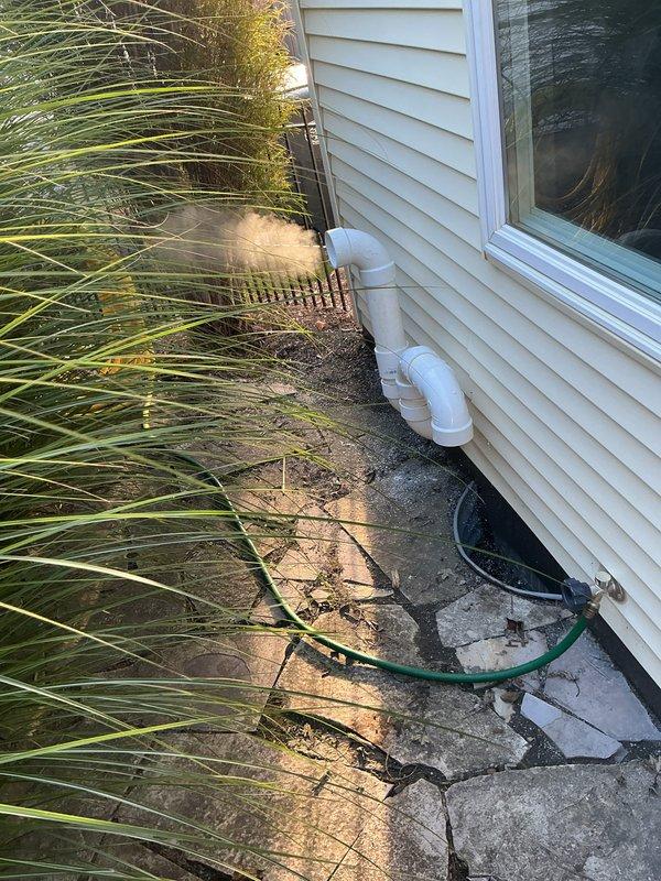 Completed installation of outdoor PVC termination piping for new furnace system. Properly routed and secured white PVC intake and exhaust pipes through exterior wall with appropriate mounting brackets, ensuring proper pitch for condensate drainage and code-compliant clearances from windows and building openings.