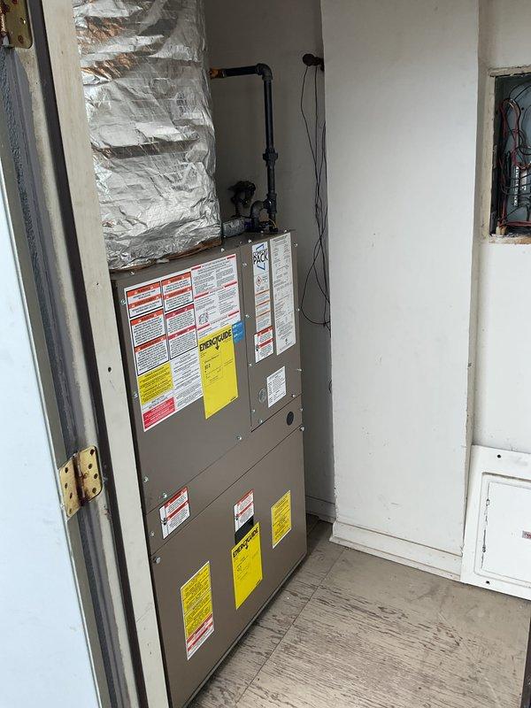 Installed NCP ComfortPack air handler unit in interior utility closet with proper ductwork connections and electrical hookup. Unit mounted vertically with insulated supply duct secured above and all safety labels properly displayed. Verified all plumbing connections, valves, and condensate drainage components are properly installed and accessible through exterior foundation access point.