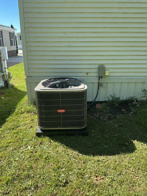 Completed installation of new Bryant outdoor air conditioning unit and evaporator coil system at residential property. Unit installed on concrete pad with proper gravel base for drainage and stability. Connected refrigerant lines with brass fittings, established electrical service with dedicated disconnect box and conduit run to exterior wall of structure. System charged with Puron refrigerant per manufacturer specifications. Verified all electrical connections, tested unit operation, and confirmed proper cooling cycle functionality upon startup.