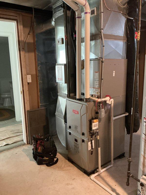 Completed full HVAC system installation including new furnace, air conditioning unit, and humidifier in residential basement utility area. Installed furnace and air handler against interior wall framing with proper clearances, ran copper refrigerant lines from indoor unit through ceiling to exterior condensing unit, and secured all piping with appropriate straps and hangers. Installed white PVC condensate drain line routed through exterior wall with proper termination and upward-facing opening to prevent debris entry. Connected all electrical components, installed flexible conduit for wiring protection, and verified proper operation of all equipment. System tested and confirmed operational with all components functioning as designed.