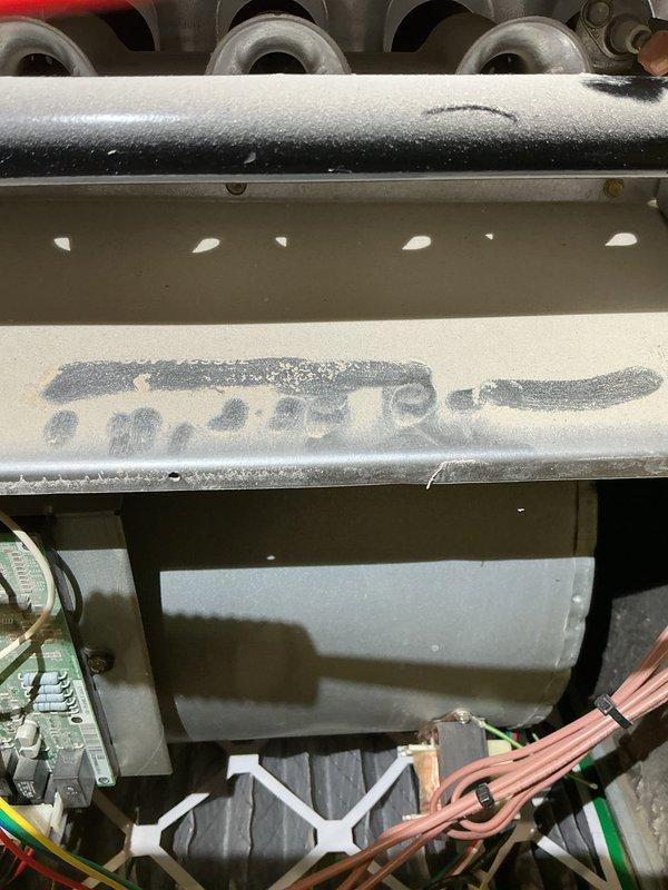 Responded to customer report of smell coming from ductwork. Upon inspection, discovered extensive frost and ice accumulation on evaporator coil assembly and refrigerant lines, indicating system operating in cooling mode or experiencing significant airflow restriction. Inspected gas valve, blower motor housing, and electrical connections on furnace unit, which appeared intact with proper wiring configurations. The heavy frost buildup on upper refrigerant piping and coil surfaces suggests possible thermostat misconfiguration, low refrigerant charge, or restricted airflow causing the coil to freeze and create unusual odors when system cycles. Documented conditions with photographs showing gas valve assembly with multi-colored wire connections and the frozen evaporator coil with ice coating on cylindrical refrigerant line and metal housing components.