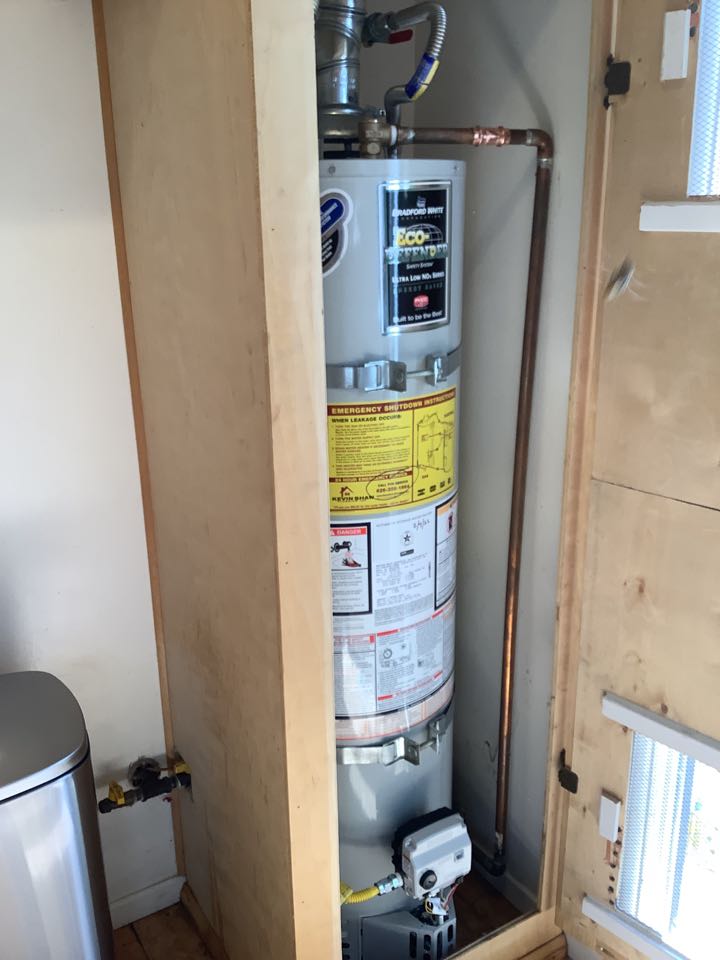 Plumber working on replacing Hot water heater that is leaking inside kitchen cabinet replacing with new Bradford White with all necessary code upgrades 