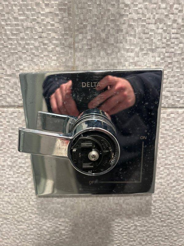 Responded to service call regarding a Delta shower control valve issue. Upon inspection of the modern bathroom featuring a rainfall showerhead and recessed lighting, diagnosed functionality problems with the chrome Delta control valve mounted on textured gray tile wall. Repaired the valve mechanism and tested water flow to ensure proper operation of the ON/OFF functionality.