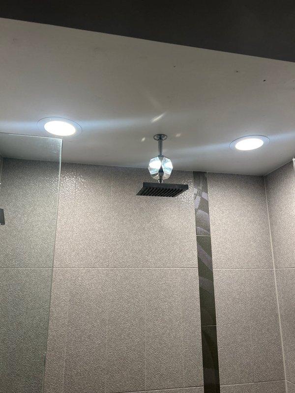 Responded to service call regarding a Delta shower control valve issue. Upon inspection of the modern bathroom featuring a rainfall showerhead and recessed lighting, diagnosed functionality problems with the chrome Delta control valve mounted on textured gray tile wall. Repaired the valve mechanism and tested water flow to ensure proper operation of the ON/OFF functionality.