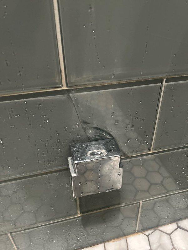 Responded to customer complaint of second-floor shower leak. Inspected detachable showerhead, flexible metal hose, and wall-mounted chrome fixture serving as diverter/mount. Identified and repaired water leakage issue at the connection point of the diverter unit on the tiled wall.