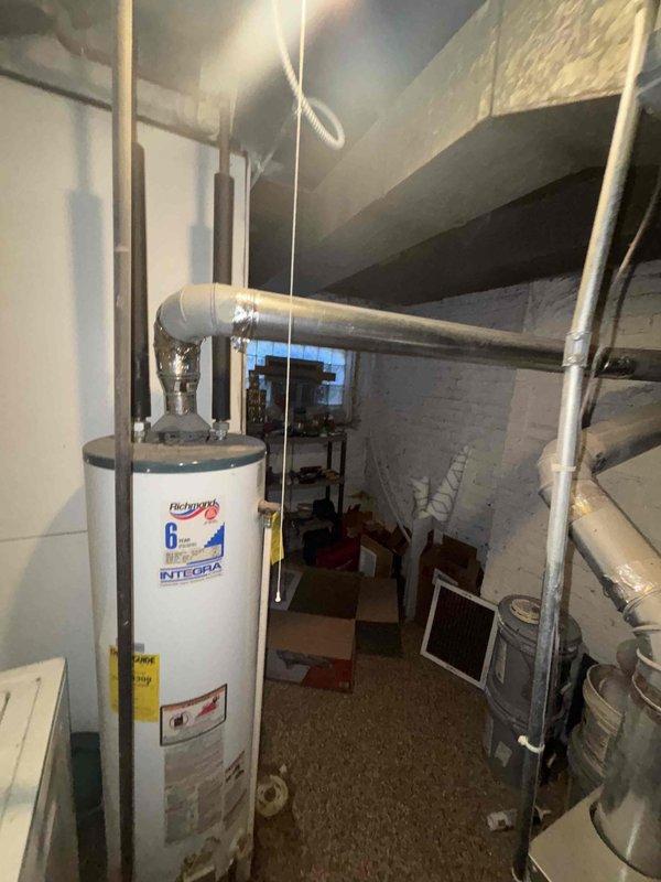 Inspected customer's existing Richmond Integra water heater, which shows active leaking from tank bottom and significant corrosion at base, confirming unit requires replacement. Documented current installation configuration including PVC venting and plumbing connections to facilitate accurate estimate for new water heater installation.