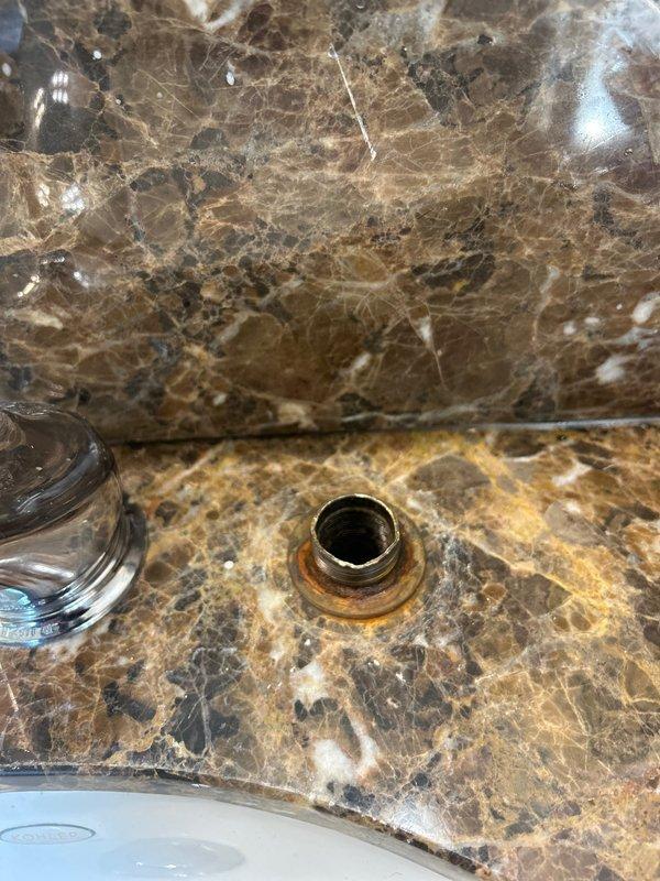 Responded to a rescheduled service call for a bathroom faucet with leaking and stuck cartridge nut issues. Upon inspection, observed corrosion around the drain fixture with visible rust formation. Assessed water heater system for potential connection to faucet pressure problems.