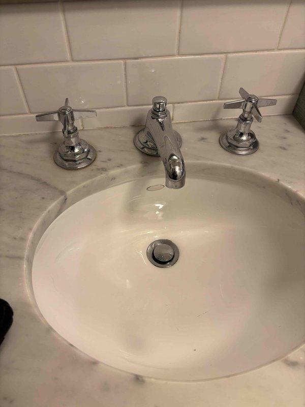 Responded to priority service call regarding toilet not filling properly. Inspected water supply system and accessed shutoff valve assembly in utility space to restore proper water flow. Also evaluated two bathroom sink cartridges for potential replacement as requested by customer Rachel, observing chrome fixtures on marble countertop with subway tile backsplash in good overall condition.