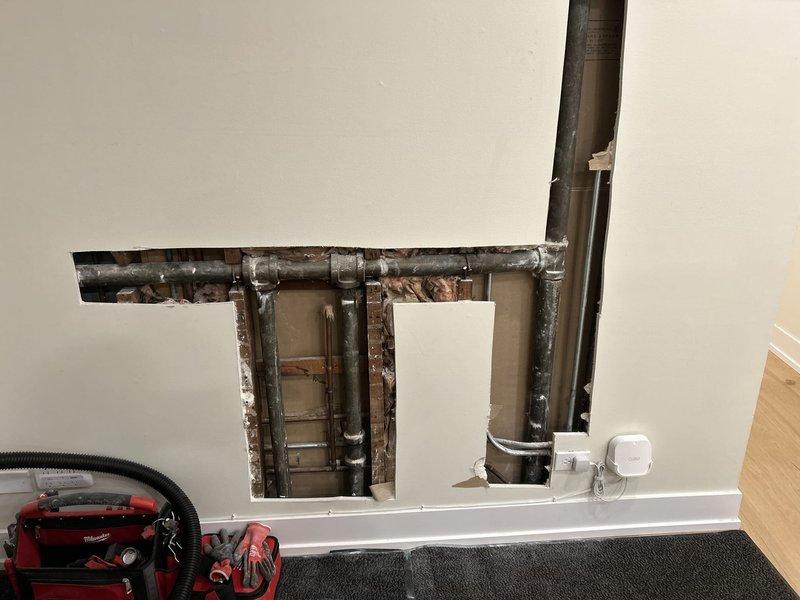 Performed inspection of client's wall to investigate reported foul odor. Cut T-shaped opening in drywall to access and examine plumbing infrastructure, revealing multiple galvanized steel pipes with visible connections. Assessment confirmed client's suspicion of corroded piping, which was identified as the likely source of the odor issue.