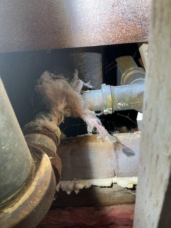 Responded to call back for Jon to inspect deteriorated plumbing infrastructure. Documented significant corrosion and oxidation on main metal pipe with extensive rusting and mineral buildup. Noted damaged insulation with loose fibers around pipe connections in the mechanical space, indicating need for comprehensive repair/replacement of aging system components.