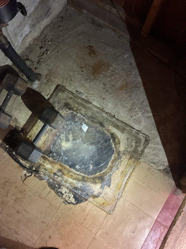 Responded to service call for clogged basement drain system. Inspected the corroded floor drain/sump basin showing significant signs of moisture damage and rust. Serviced the drainage system, clearing blockage and ensuring proper function of the connected black plumbing pipes and sump pump installation.