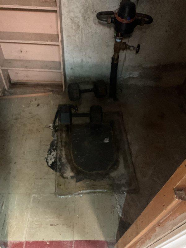 Responded to service call for clogged basement drain system. Inspected the corroded floor drain/sump basin showing significant signs of moisture damage and rust. Serviced the drainage system, clearing blockage and ensuring proper function of the connected black plumbing pipes and sump pump installation.