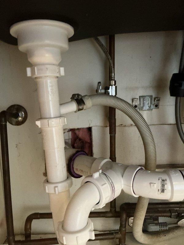 Responded to a basement leak service call at residential property. Upon inspection, identified and serviced the under-sink drainage system, which included checking the PVC P-trap configuration, examining the flexible corrugated drain hose connections, and verifying integrity of all pipe joints and metal clamps. Confirmed proper function of the drainage assembly and resolved the reported leak issue.