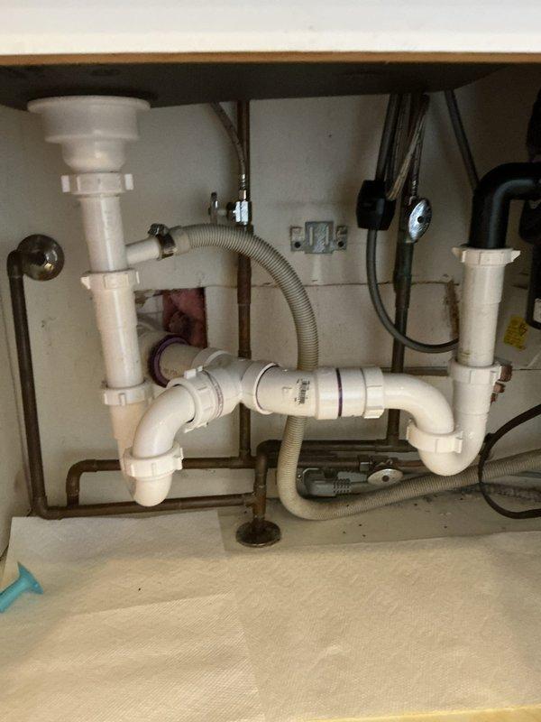 Responded to a basement leak service call at residential property. Upon inspection, identified and serviced the under-sink drainage system, which included checking the PVC P-trap configuration, examining the flexible corrugated drain hose connections, and verifying integrity of all pipe joints and metal clamps. Confirmed proper function of the drainage assembly and resolved the reported leak issue.