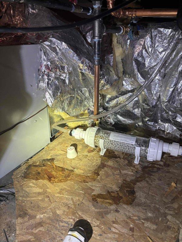 Inspected tankless water heater system after customer reported leak sensor activation. Identified issue with condensate drainage system where water was backing up around condensate output. Observed Condensate Neutralization Capsule was approximately 75% full but not properly draining. Scheduled follow-up appointment to install condensate neutralizer under warranty, noting that hard plastic piping will be required for the condensate drainage due to high attic temperatures.
