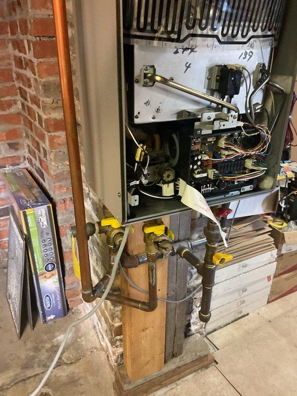 Responded to customer complaint of tankless water heater leaking from base with no hot water output. Upon inspection, found water leakage at base of unit mounted on brick wall. Diagnostic assessment revealed internal component failure affecting water containment system. Opened unit to examine circuit boards, wiring, and plumbing connections. Traced issue to compromised seal at copper pipe junction. Repaired connection and tested system functionality to confirm proper operation and elimination of leak.