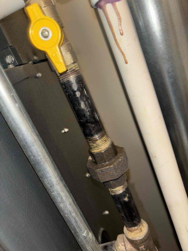 Diagnosed non-operational Novian tankless water heater in utility closet. Visual inspection revealed potential water leak on adjacent PVC pipe with visible rust staining. Accessed internal components of unit through front panel to evaluate control board, valves, and circuitry for proper functionality.