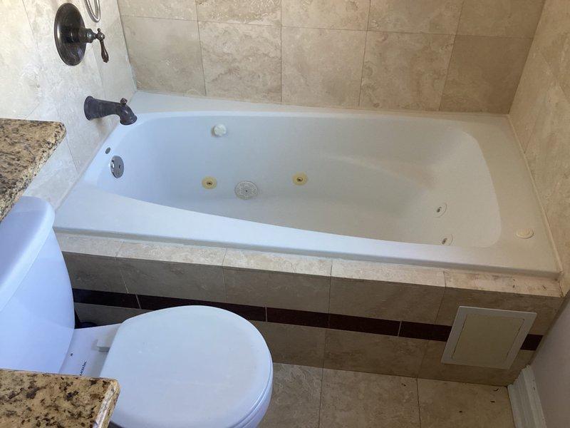 Responded to a callback for Frank Basi to assess jetted bathtub replacement. Inspected existing jacuzzi tub/shower combination with oil-rubbed bronze fixtures and beige tile surround. Documented current installation condition for proper replacement specifications.