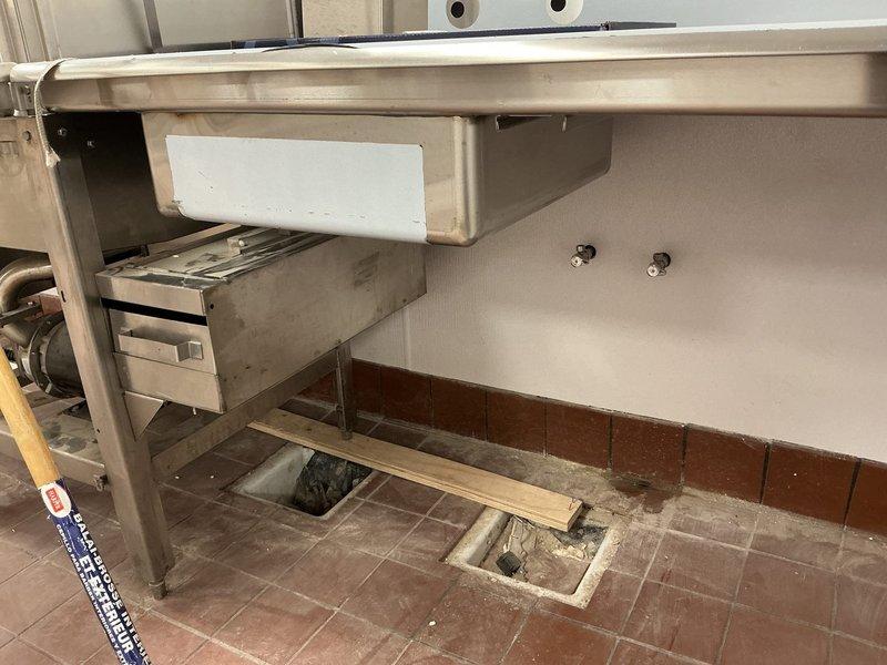 Performed site assessment at commercial property to evaluate requirements for new drain installations for multiple sinks. Inspected existing stainless steel workstations in the kitchen area, noting current drainage configuration and floor access points. Identified necessary connection points to main sewer line through the terracotta-tiled floor where access panel was located. Provided comprehensive estimate for commercial drain installation project.