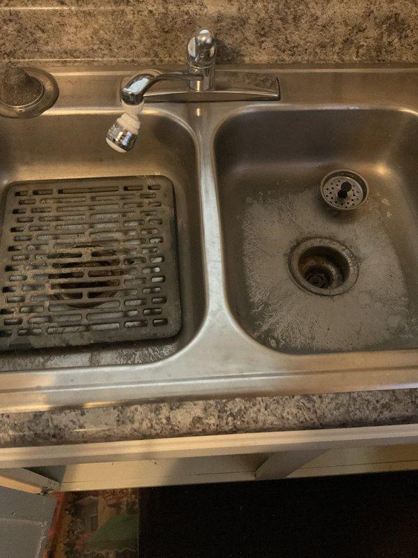Diagnosed multiple kitchen sink clogs on second and third floors. Cleaned out grease trap under sink but clog persisted. Upon further inspection, identified a water leak from chrome faucet connection requiring containment with collection bucket. Recommended professional drain cleaning service to address persistent clog beyond trap area.