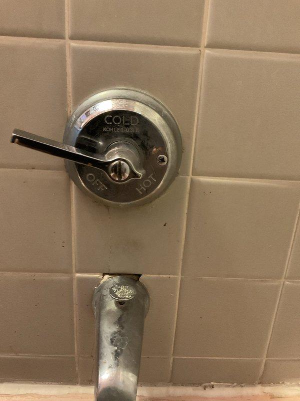 Performed flood control maintenance and inspected Kohler shower/tub fixture with visible leakage. Observed significant mineral buildup and rust staining around the drain area of pink porcelain tub, along with deterioration of chrome spout and handle. Addressed water control issues to prevent further damage to the aging bathroom fixtures.
