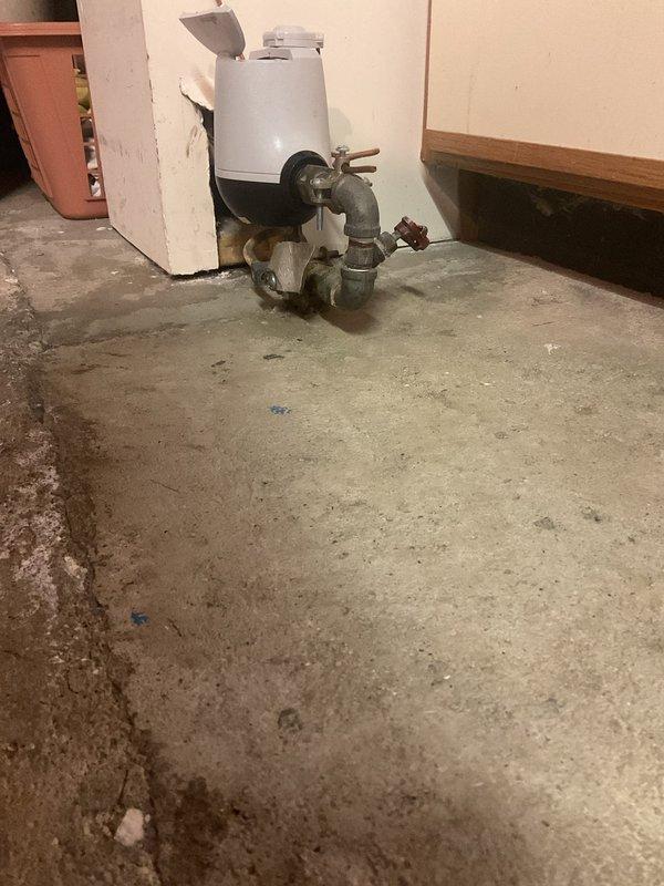 Responded to first morning service call sold by Joey. Upon inspection, found water heater/hot water appliance in utility area with corroded plumbing connections and evidence of moisture damage on concrete floor. Documented existing conditions with photos before proceeding with necessary repairs.