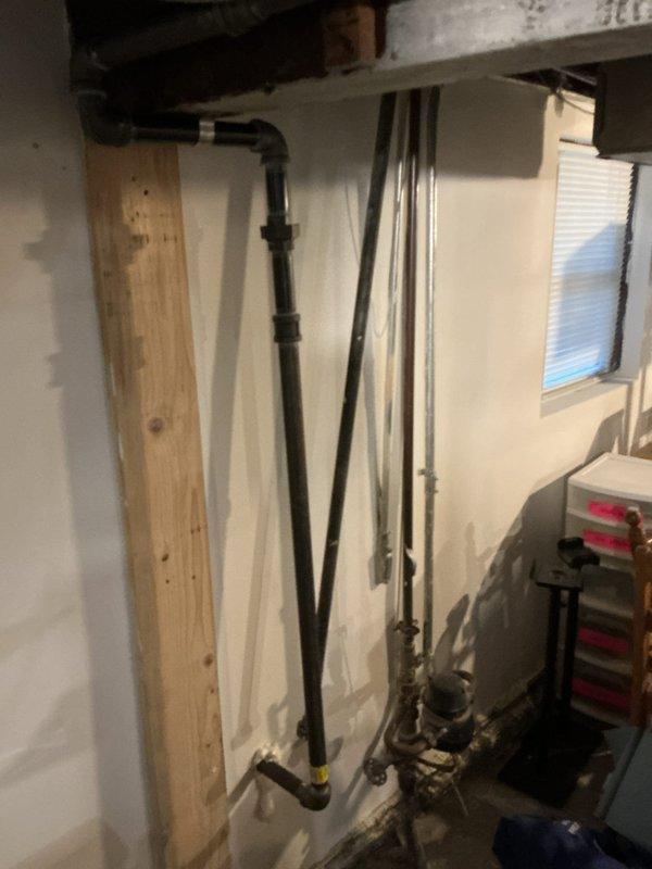 Completed gas repipe at front of house, relocated slop sink against wall, and sealed exterior pipe penetration with spray foam and silicone. Installed various sized nipples (24", 36", 48") to complete the installation and ensure proper gas supply to resolve intermittent hot water issues.