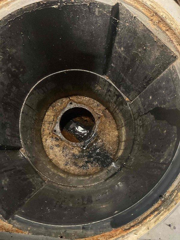 Conducted inspection of sewer system with notable water turbulence and discharge visible in the main line. Documented significant debris accumulation and potential corrosion in the cylindrical drain fixture, with sediment buildup around the central drain opening that could contribute to flooding issues.