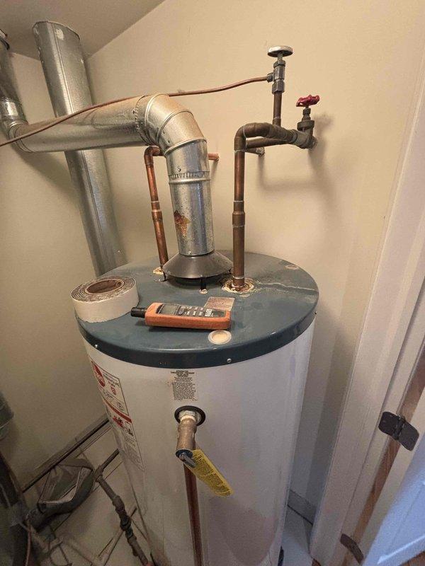 Inspected 20+ year old 75-gallon water heater exhibiting active leakage from top connections. Unit shows significant age deterioration with discolored copper pipes and deteriorating connections. Recommended full replacement due to tank age and active leak condition.