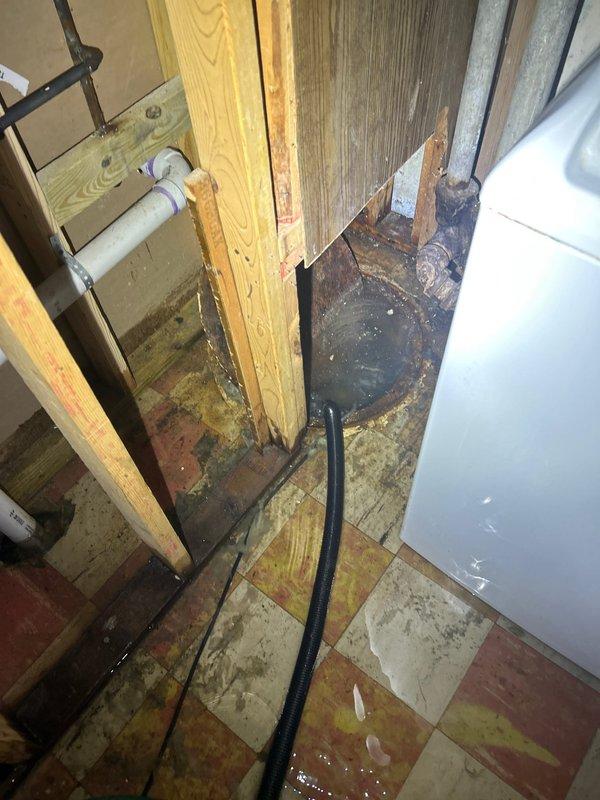 Responded to customer report of basement flooding due to sewer line issue. Inspection revealed standing water on tile floor with visible moisture damage to wooden framing elements and studs at their bases. Observed potential water damage extending to the exterior area, with signs of deterioration in surrounding landscape. Diagnosed as sewer line backup causing water intrusion through basement foundation.