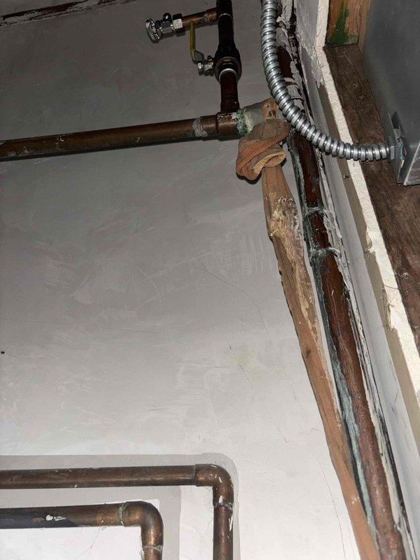 Conducted thorough inspection of 22-year-old GE SmartWater water heater installation, noting significant age-related wear including oxidation and patina formation on copper pipes at connection points. Evaluated current setup featuring copper supply lines, PVC components, and shut-off valves to determine replacement options suitable for the existing confined utility space configuration.