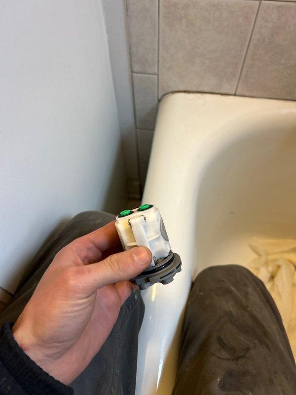Responded to a priority service call to address damaged wall panel and plumbing valve issue. Replaced faulty bathtub valve assembly with new component featuring green indicator buttons. Repaired damaged drywall section near the door frame where surface material had cracked.