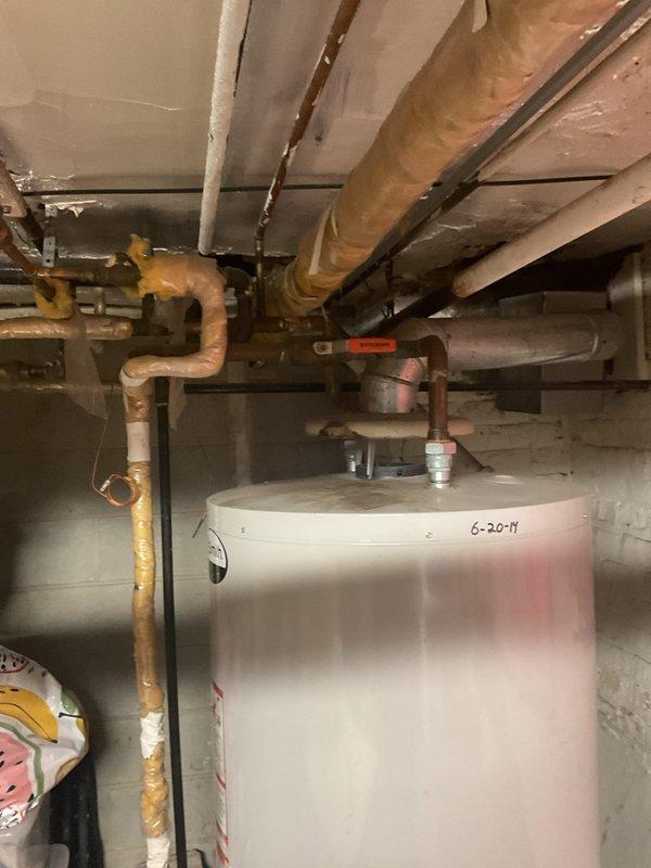 Conducted inspection of a 10-year-old water heater serving a 3-unit building. Identified minimal hot water supply issue in tank system installed June 2017. Observed aging infrastructure including deteriorated insulation on copper pipes and compromised ventilation system. Recommended replacement with appropriately sized unit to restore adequate hot water capacity for multi-unit requirements.