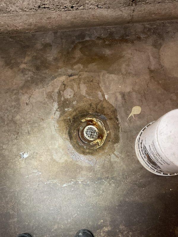Performed site assessment on concrete floor drain showing significant mineral buildup and water staining around drain opening. Conducted inspection of drainage system and provided customer with hydrojetting options to clear blockage and restore proper drainage function. Floor drain showed evidence of prolonged water exposure requiring professional intervention.