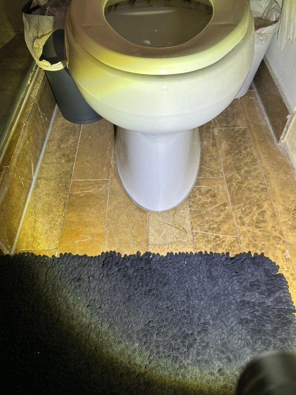 Responded to follow-up service call for water leak diagnosis. Inspected bathroom with reported ceiling damage below. Examination of toilet revealed bowl discoloration and potential seal issues, while shower area showed signs of water intrusion at tile joints and drain connection. Located source of leak at shower drain assembly requiring resealing and toilet flange that needed replacement to prevent further water damage to ceiling below.