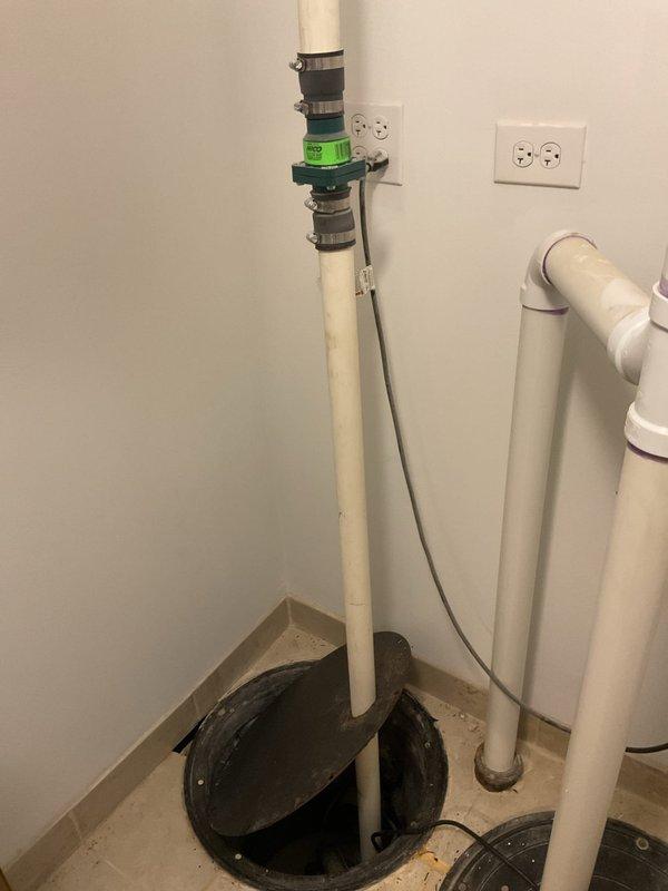 Inspected existing sump pump system in basement that customer reported as non-operational since property purchase. Observed complete pump assembly including PVC discharge piping with green check valve and multiple connection points. Diagnosed failed SUMPRO unit and recommended replacement to restore basement water management functionality.