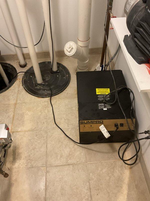 Inspected existing sump pump system in basement that customer reported as non-operational since property purchase. Observed complete pump assembly including PVC discharge piping with green check valve and multiple connection points. Diagnosed failed SUMPRO unit and recommended replacement to restore basement water management functionality.